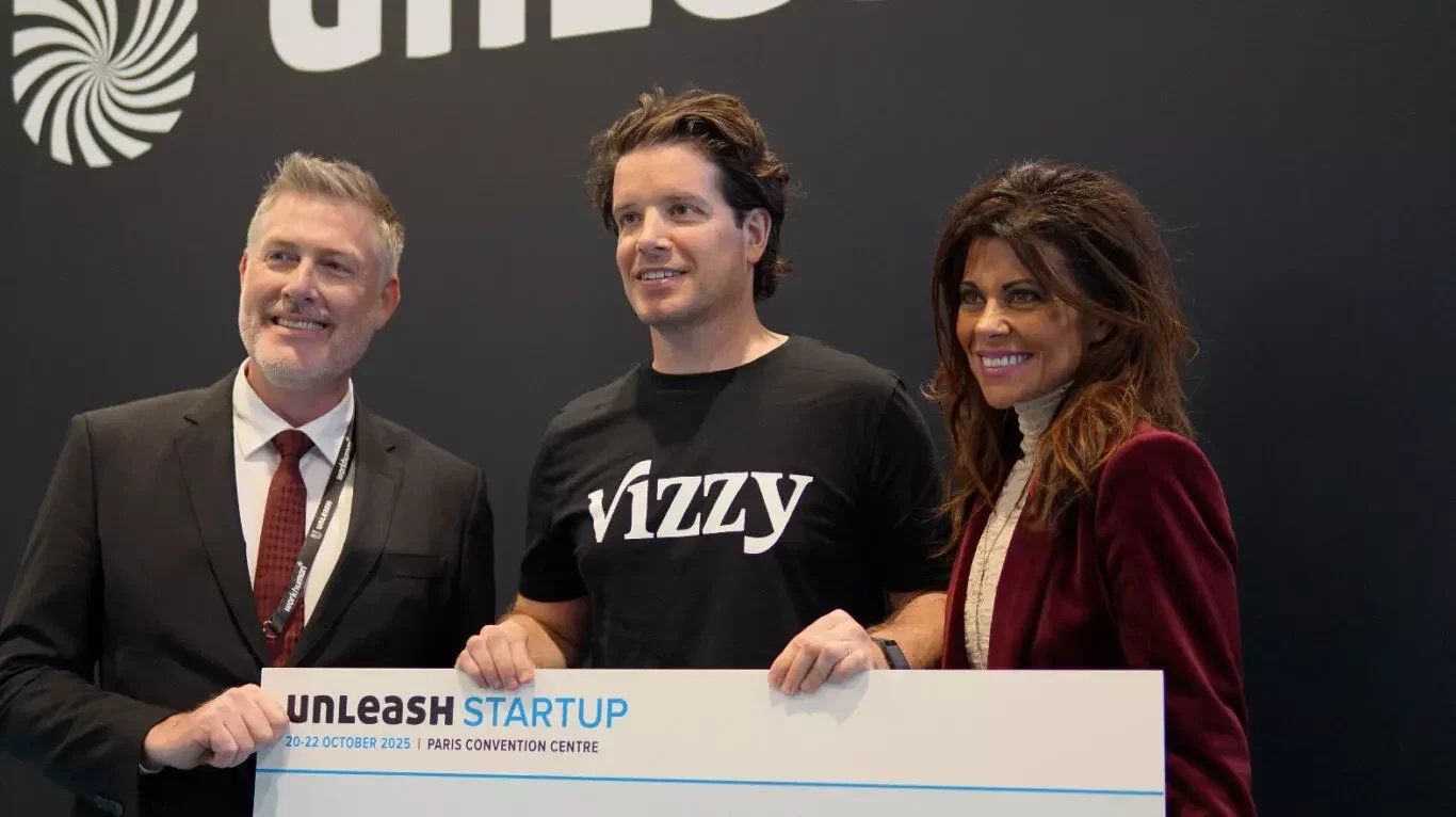 Vizzy founder poses with UNLEASH Startup Award organisers holding the winner's sign at UNLEASH World 2025.