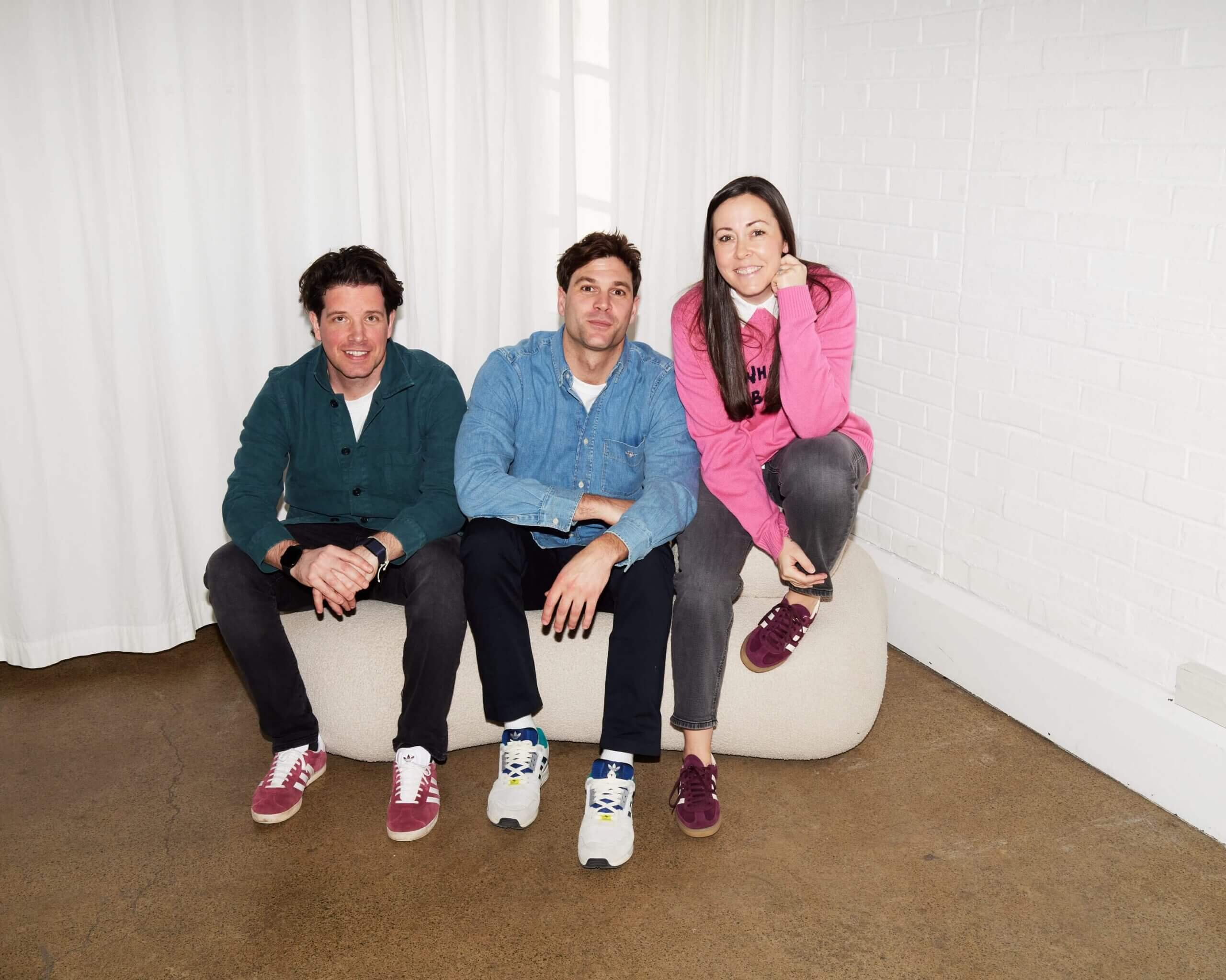 Vizzy co-founders Chris Woodward-Jones, Joe Woodward and Jess Woodward-Jones sitting together on a cream boucle bench